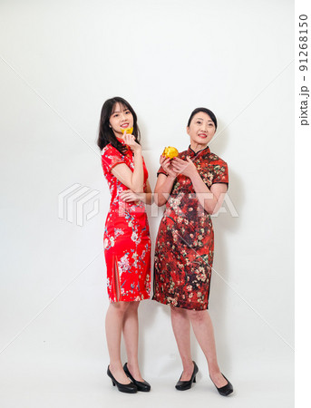 Portrait of asian young woman and elder woman both wearing traditional cheongsam qipao dress showing Gold ingot and pig meaning "May wealth come generously to you" on white background. 91268150