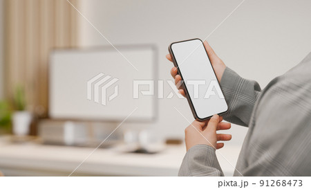 A businesswoman holding a smartphone mockup over blurred minimal office desk A businesswoman holding a smartphone mockup over blurred minimal office desk 91268473