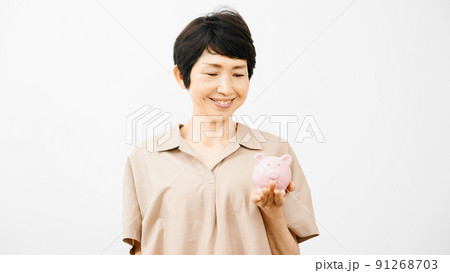 ブタの貯金箱を持って笑うミドル女性	 91268703