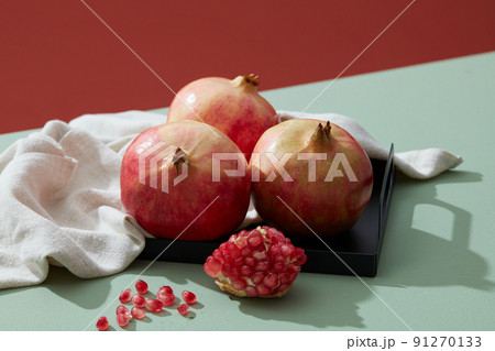 Close-up of red pomegranate in tray with linens on green table . Minimalism Close-up of red pomegranate in tray with linens on green table . Minimalism 91270133