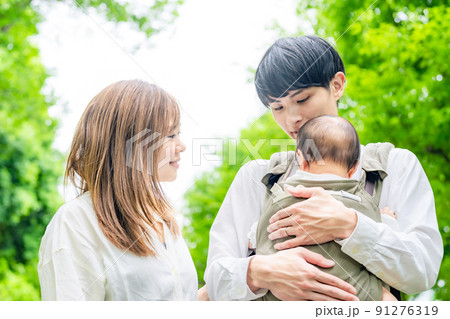 赤ちゃんを抱っこして散歩するカップル 91276319