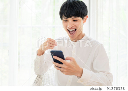 スマホを見て興奮する男性 91276328