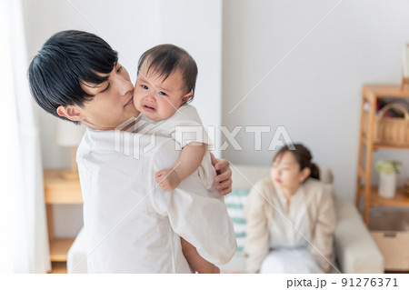 泣いている赤ちゃんをあやす父親 91276371