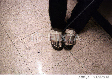 タイルの床にエスニックなサンダルの両足 91282918