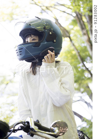 バイク女子イメージ　出発前にインカムの電源を入れる若い女性 91283002