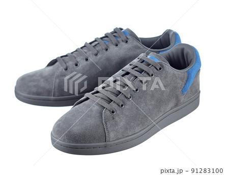 Beautiful pair of fashionable modern sneakers made of gray suede with inserts of bright blue suede in the back, lace-up, isolated on a white background. 91283100