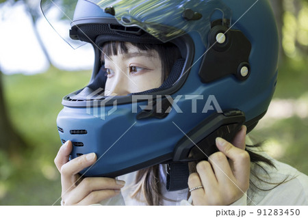 バイク女子イメージ　出発前にインカムの電源を入れる若い女性 91283450