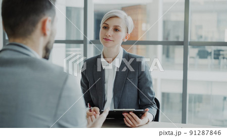 HR businesswoman having job interview with young man in suit and watching his resume application in modern office HR businesswoman having job interview with young man in suit and watching his resume application in modern office 91287846
