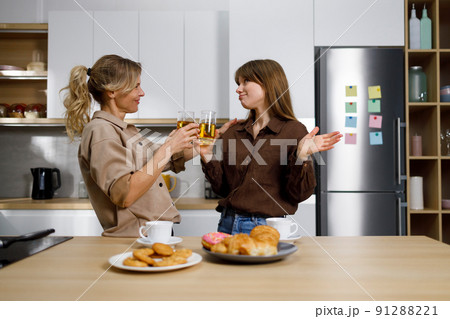 Daughter and mother drinking juice and talking about personal things in the kitchen 91288221
