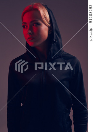 Young pretty woman wearing a black hood and shorts on dark background 91288292