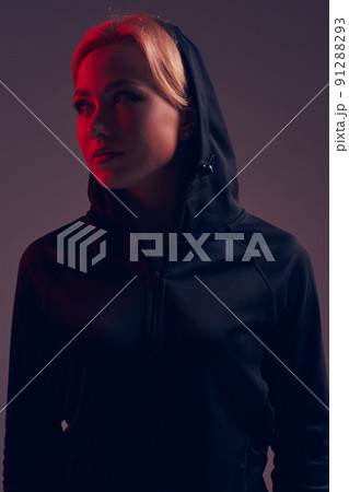 Young pretty woman wearing a black hood and shorts on dark background 91288293