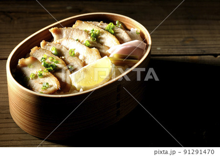 曲げわっぱに漬物とカットレモンと豚トロが入っている焼肉弁当 91291470