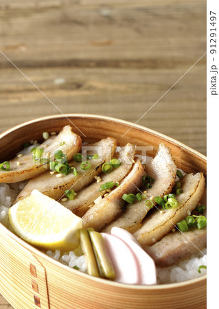 曲げわっぱに漬物とカットレモンと豚トロが入っている焼肉弁当 91291497