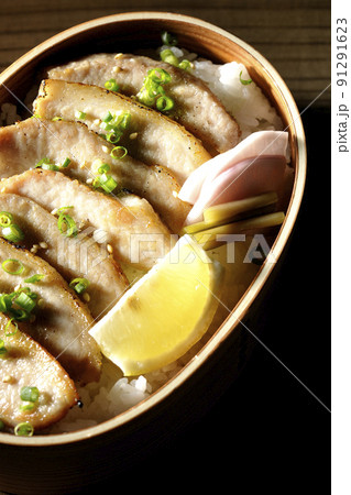 曲げわっぱに漬物とカットレモンと豚トロが入っている焼肉弁当を俯瞰で撮影 91291623