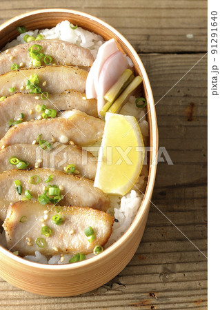 曲げわっぱに漬物とカットレモンと豚トロが入っている焼肉弁当を俯瞰で撮影 91291640