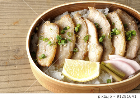 曲げわっぱに漬物とカットレモンと豚トロが入っている焼肉弁当を俯瞰で撮影 91291641