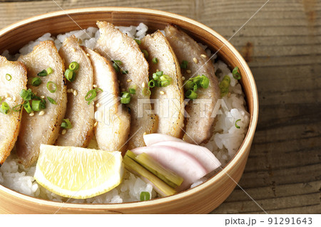 曲げわっぱに漬物とカットレモンと豚トロが入っている焼肉弁当を俯瞰で撮影 91291643