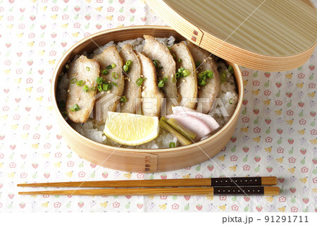 曲げわっぱに漬物とカットレモンと豚トロが入っている焼肉弁当を俯瞰で撮影 91291711