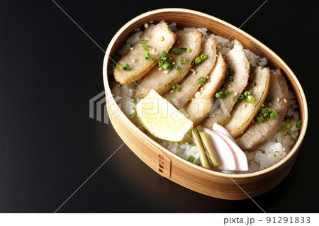 曲げわっぱに漬物とカットレモンと豚トロが入っている焼肉弁当を黒背景で俯瞰撮影 91291833