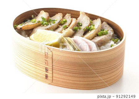 曲げわっぱに漬物とカットレモンと豚トロが入っている焼肉弁当を白背景で撮影 91292149