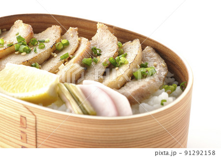曲げわっぱに漬物とカットレモンと豚トロが入っている焼肉弁当を白背景で撮影 91292158