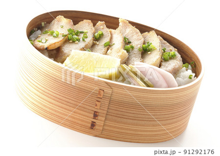 曲げわっぱに漬物とカットレモンと豚トロが入っている焼肉弁当を白背景で撮影 91292176