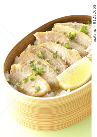 曲げわっぱに漬物とカットレモンと豚トロが入っている焼肉弁当 91292608