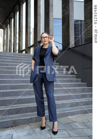 Elegant business woman in glasses standing outside a modern office building 91293486