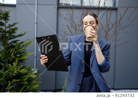 Business woman with clipboard drinking coffee outdoors 91293732