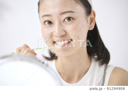鏡を見ながら歯磨きをする若いの女性 91294908