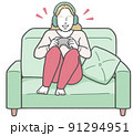 ヘッドフォンを着けてソファに座り、1人でテレビゲームを楽しむ若い西洋人女性 ヘッドフォンを着けてソファに座り、1人でテレビゲームを楽しむ若い西洋人女性 91294951