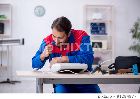 Young male repairman repairing heater 91294977