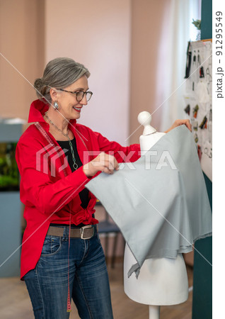Woman hanging fabric on dummy sideways to camera 91295549