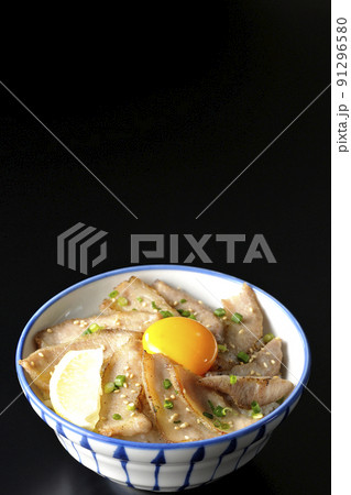 カットレモンと卵黄が乗った豚トロ丼、焼き肉丼を黒背景で撮影 91296580