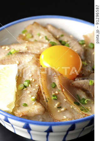 カットレモンと卵黄が乗った豚トロ丼、焼き肉丼を黒背景で撮影 91296587