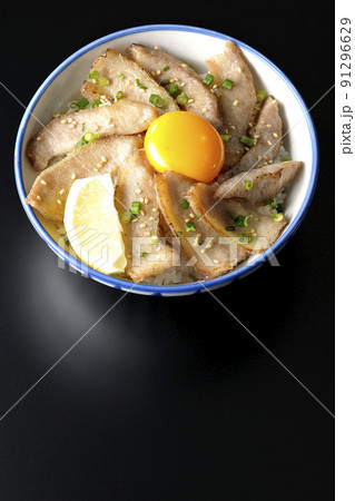 カットレモンと卵黄が乗った豚トロ丼、焼き肉丼を黒背景で俯瞰撮影 91296629