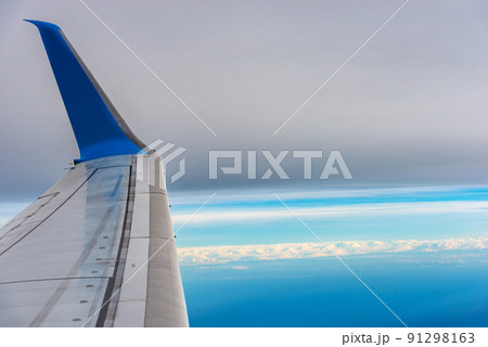 Commercial Airplane Flying over the Clouds - Looking Through the Plane Window 91298163