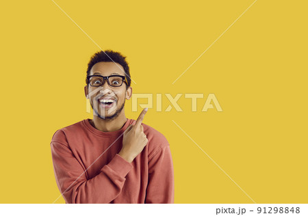 Happy excited university student pointing his finger to the side on copy space background Happy excited university student pointing his finger to the side on copy space background 91298848