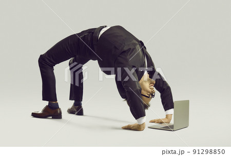 Happy flexible businessman in suit doing yoga while working on his laptop computer Happy flexible businessman in suit doing yoga while working on his laptop computer 91298850