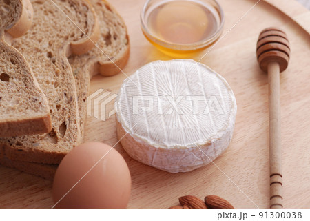 fresh cheeses , honey, egg, and bread on a plate  91300038