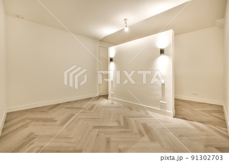 Interior of empty modern apartment with geometric design with entrance door and white walls and parquet floor illuminated with lamp Interior of empty modern apartment with geometric design with entrance door and white walls and parquet floor illuminated with lamp 91302703