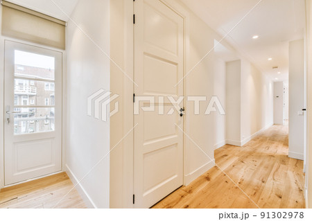 Light narrow hallway with many doors in white walls and glowing lamp over lumber floor 91302978