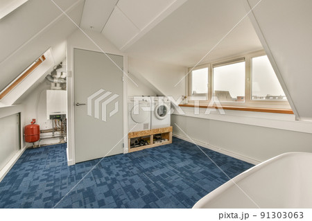 Sinks with washing machine and clean bathtub located near shower box with glass door in modern bathroom with blue tiled floors Sinks with washing machine and clean bathtub located near shower box with glass door in modern bathroom with blue tiled floors 91303063