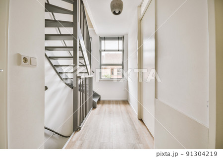 A window next to a gray spiral staircase connecting the floors of a modern house 91304219