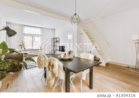 Couches and table located near TV against dining area of spacious room in contemporary apartment 91304316