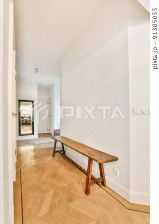 Light narrow hallway with many doors in white walls and glowing lamp over lumber floor 91305055