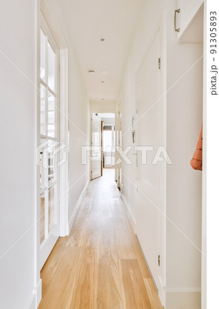 Light narrow hallway with many doors in white walls and glowing lamp over lumber floor Light narrow hallway with many doors in white walls and glowing lamp over lumber floor 91305893