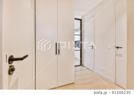Light narrow hallway with many doors in white walls and glowing lamp over lumber floor Light narrow hallway with many doors in white walls and glowing lamp over lumber floor 91306230