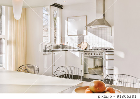 Interior of a bright kitchen and dining room with balcony doors in a modern apartment at daytime Interior of a bright kitchen and dining room with balcony doors in a modern apartment at daytime 91306281