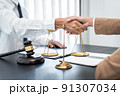 Businesswoman shaking hands with Professional male lawyer after discussing a good deal of contract in the courtroom, Concepts of law, Judge gavel with scales of justice 91307034